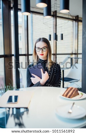beautiful business woman sitting in a restaurant by the window holding a book