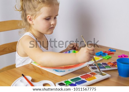 Happy young girl draws rainbow