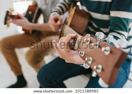 Learning to play the guitar. Music education and extracurricular lessons. Hobbies and enthusiasm for playing guitar and singing songs. Royalty-Free Stock Photo #1011588985