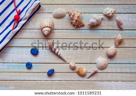 Seashells shaped heart on a wooden background top view.