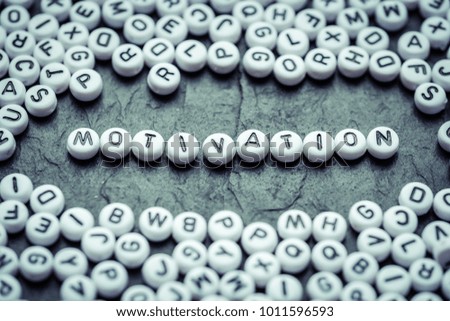 Motivation word made from small white letters on black stone background  