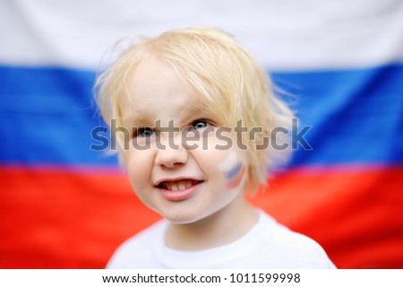 Portrait of cute little boy with russian flag on background. Fans child supporting and cheering their national team at the sporting games