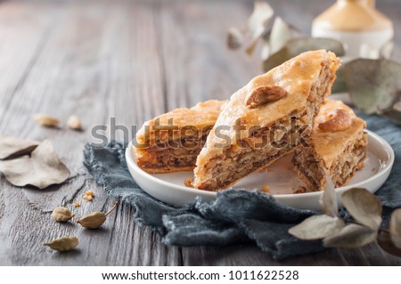 Traditional arabic dessert baklava with  cashew, walnuts and cardamom with an eucalyptus branch on a wooden table. Homemade baklava with nuts and honey. Royalty-Free Stock Photo #1011622528