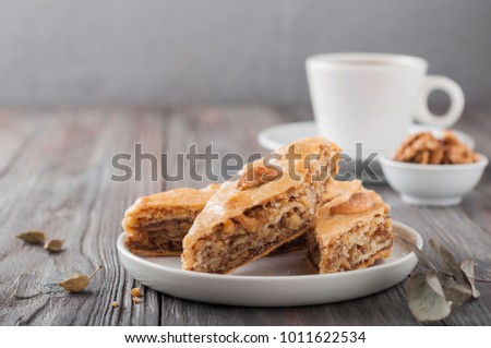 Traditional arabic dessert baklava with a cup of coffee, cashew, walnuts and cardamom with an eucalyptus branch on a wooden table. Homemade baklava with nuts and honey. Royalty-Free Stock Photo #1011622534