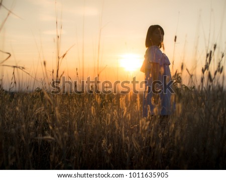 Young woman enjoying in the meadow at sunset