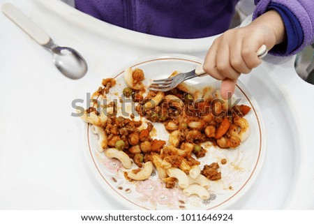 child eating food sitting in a high chair with white background stock photo