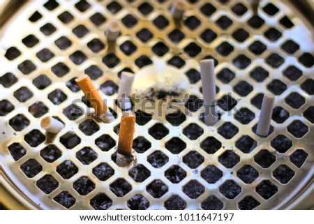 Cigarettes in ashtray at smoking area. Closeup view of big ashtray with dropped cigarettes. World no tobacco day on may 31. Selective focus.