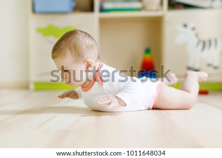 Cute baby girl learning crawling and sitting in children room