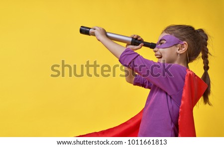 Little child is playing superhero. Kid on the background of bright ultra violet wall. Girl power concept. Yellow, red and  purple colors.