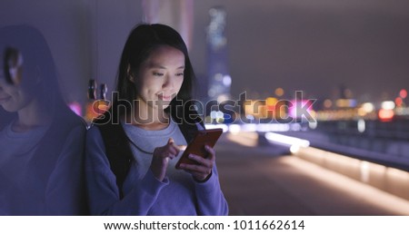 Woman looking at cellphone in the city at night 