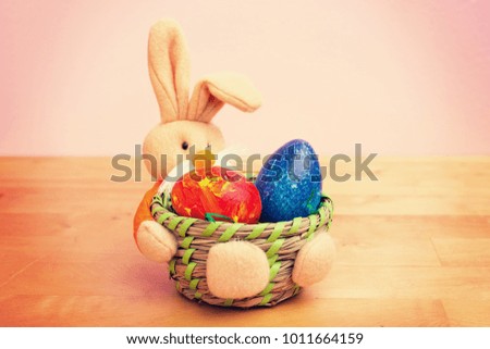 easter bunny in basket with egg in front of pink background