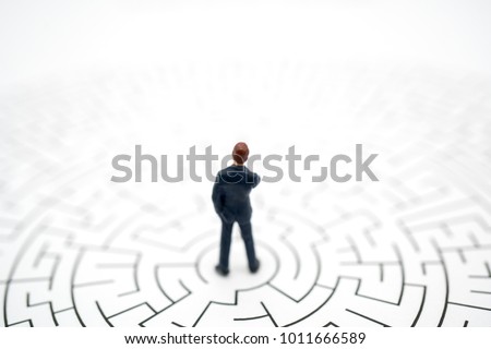 Miniature toy:Business man thinking how to solve this problem.Business obstacle,financial,business growth concept.business man stand on center of maze.