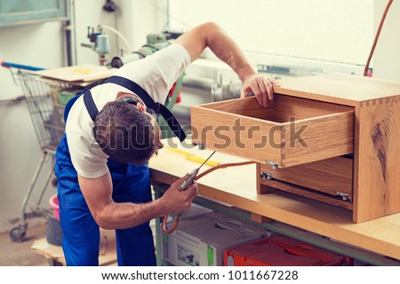 worker in blue dungarees in a carpenter's workshop Royalty-Free Stock Photo #1011667228