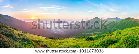 Beautiful sunrise in mountains with white fog below panorama Royalty-Free Stock Photo #1011673036