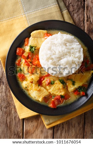 Fish stew in coconut milk with vegetables and rice close-up on a plate. Vertical top view from above
