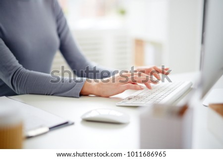 Hands of young secretary over computer keyboard typing by workplace Royalty-Free Stock Photo #1011686965