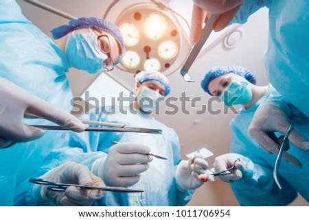 Group of surgeons in operating room with surgery equipment. Background