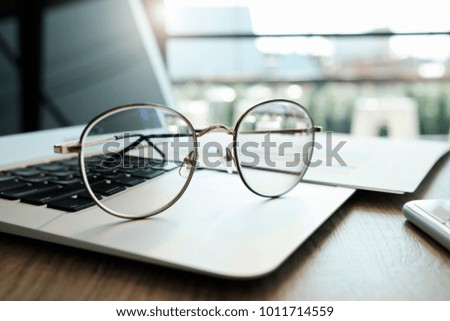 Close up of eye glasses on work desk with laptop at business workplace.