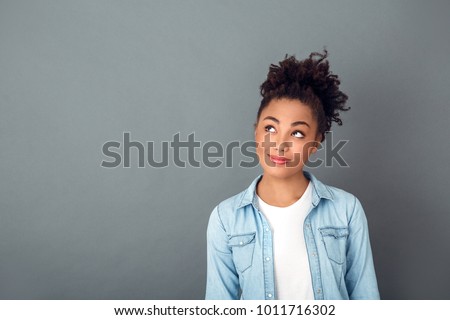 Young african woman isolated on grey wall studio casual daily lifestyle thinking close-up Royalty-Free Stock Photo #1011716302