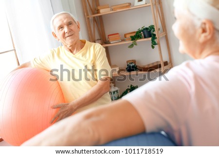 Senior couple exercise together at home health care holding balls looking on each other back view