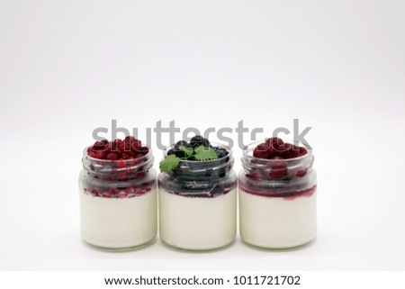 Fresh berries in the jar with the yogurt. On white background.