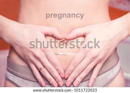 Woman holding pregnancy test in the shape of the heart from the hands, Positive pregnancy test with two strips, Motherhood, pregnancy, new life and new family concept, waiting for the child with love