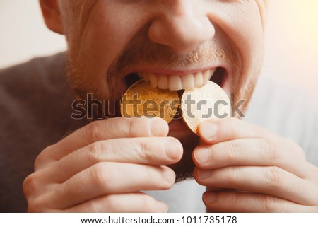 Bitcoin. Man bites a gold coin with his teeth Royalty-Free Stock Photo #1011735178