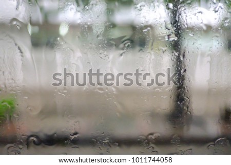 in selective focus of a rain drop on the car window with blur street side background