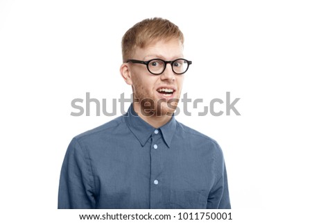 Picture of funny emotional young unshaven man wearing stylish glasses opening mouth in astonishment, being shocked with unexpected news, staring at camera in full disbelief. Shock and surprise