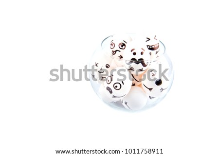 Eggs with drawn cartoon faces in a glass vase isolated on white background.