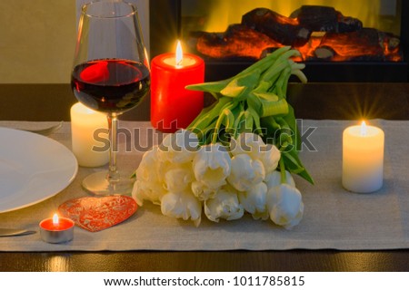 Table in front of fireplace served for romantic Valentine's day dinner