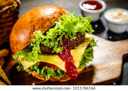 Tasty burger with chips served on cutting board 