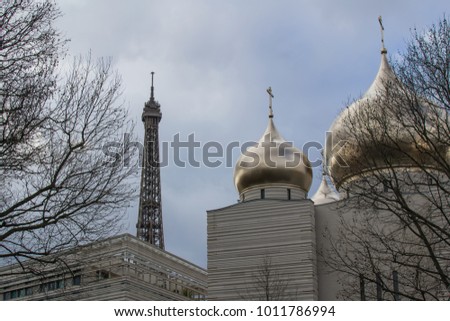 Winter skyline in Paris, view of the golden cupolas of the newly built Orthodox Churc and Russian culture center, cloudy day and trees without leaves, contrasts with the Eiffel tower in the background