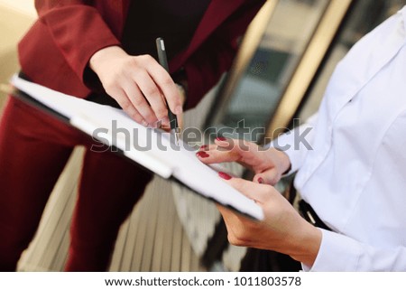 business women sign a contract or documents against the background of an office building