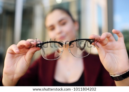 cute young girl holding glasses close-up. Optics, blzorukost, farsightedness, astigmatism. Royalty-Free Stock Photo #1011804202