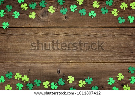 St Patricks Day double border of paper shamrocks over an old rustic wood background