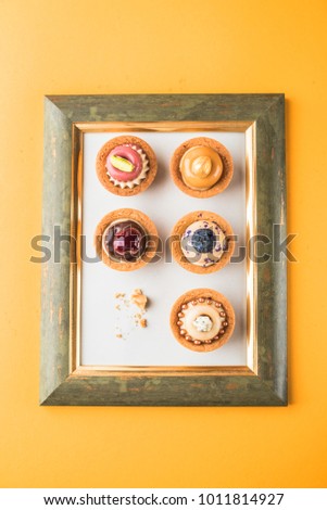 Dessert - cake tarts with fruits and berries in the frame of the picture on an orange background. Fresh delicious food.