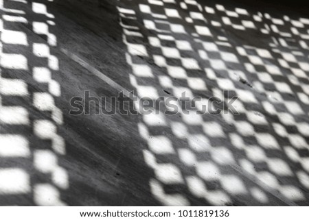 Close up view of geometric shadows of a decorative wall on the floor. Black and white rectangles and squares on the cement surface. Patterns of rectangular shapes, bands and lines. Abstract picture.