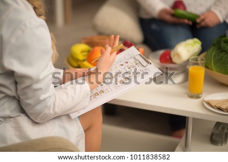 close up image of dietitian in white gown. holding die plan for patient. Royalty-Free Stock Photo #1011838582