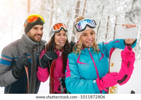 adventure, travel, hike and people concept - friends snowboarders or skiers making selfie in  forest