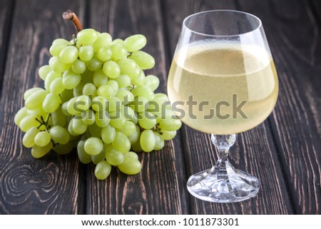 fresh green grapes and wineglass close up on wood desk
