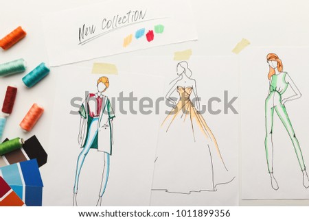 New fashion collection background. Hand drawn sketches of clothes on white board, color swatches and threads, top view. Creativity, dressmaking and design concept