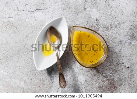 dressing for salad from olive oil and lemon in a serving dish and a silver spoon on a stone table Royalty-Free Stock Photo #1011905494