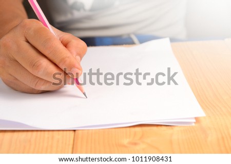 Man's hand holding pencil on white paper.