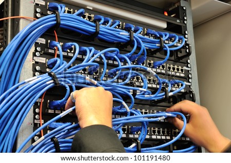 Man connecting network cables to switches Royalty-Free Stock Photo #101191480
