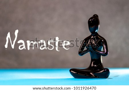 Little black figurine woman keep hands in Namaste - greeting sign. Yoga and meditation concept