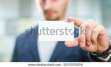 A handsome businessman showing a blank piece of paper. Close-up shot. Soft focus.