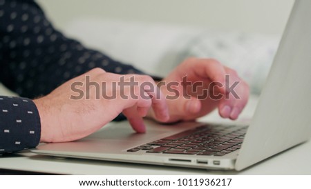 Man's hands typing on a laptop. Close-up Dolly shot. Soft focus.