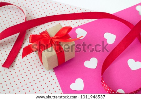 gift with a bow, on colored paper with a texture, scattered red hearts