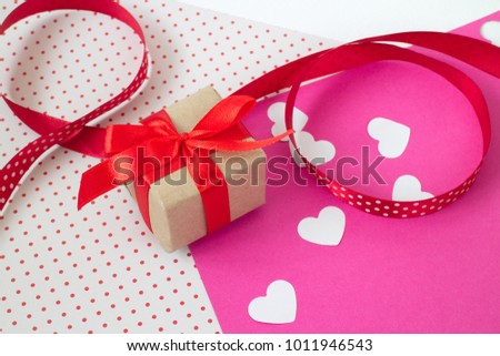 gift with a bow, on colored paper with a texture, scattered red hearts